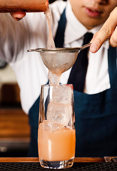 a bartender making a cocktail at the bar