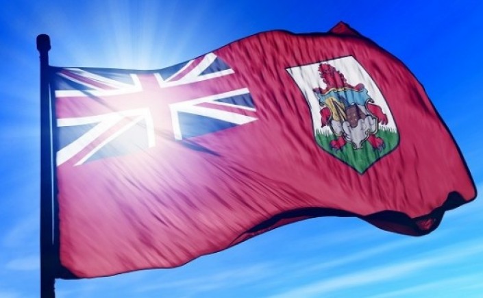 Bermuda flag blowing in the wind with the sun behind it