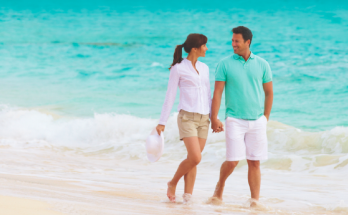Couple holding hands gazing into each other's eyes while walking along the shoreline