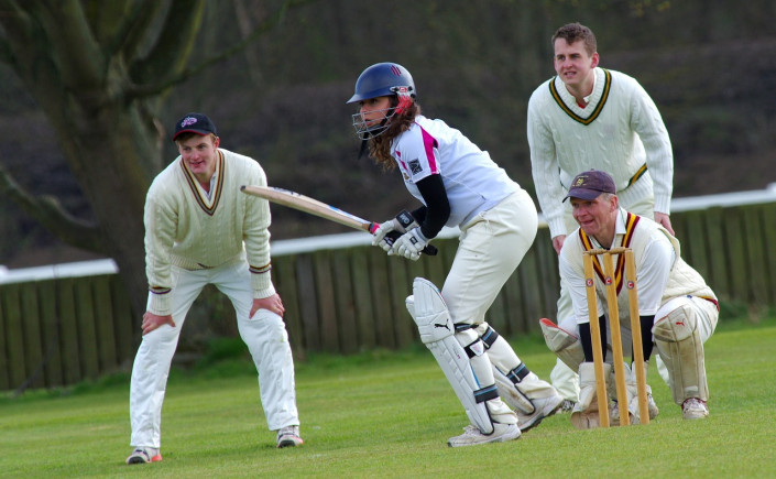 Four people playing cricket