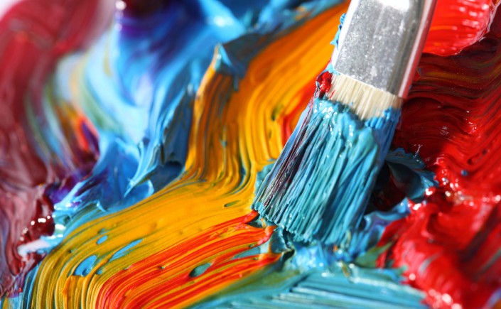 Paintbrush in progress painting abstract streaks with orange, blue, and red colors