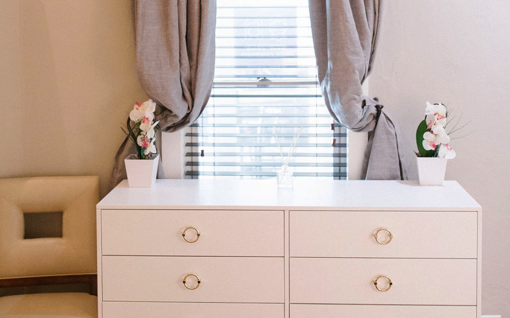 white dress table with a chair and two grey curtains