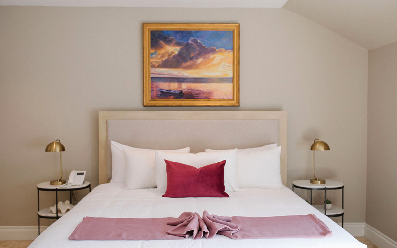 double bed with a sunrise painting and two gold side lamps