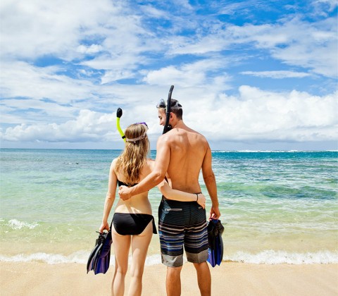 A couple wearing snorkel masks at the seashore