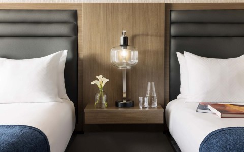 two beds side by side with a small nightstand in between with a lamp
