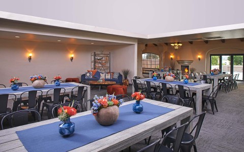 several grey wooden tables with blue cloth and flower vases