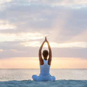 woman doing yoga on the beach with a sunrise in the background