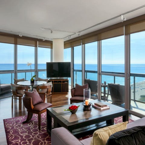 a large room with a living area and a table for dining with a view of the ocean during the day