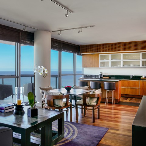 a large room with a table for dining and a kitchen with a bar top overlooking the ocean