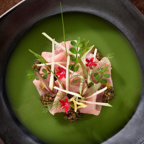 close up of a sashimi dish served on top of green finishing sauce