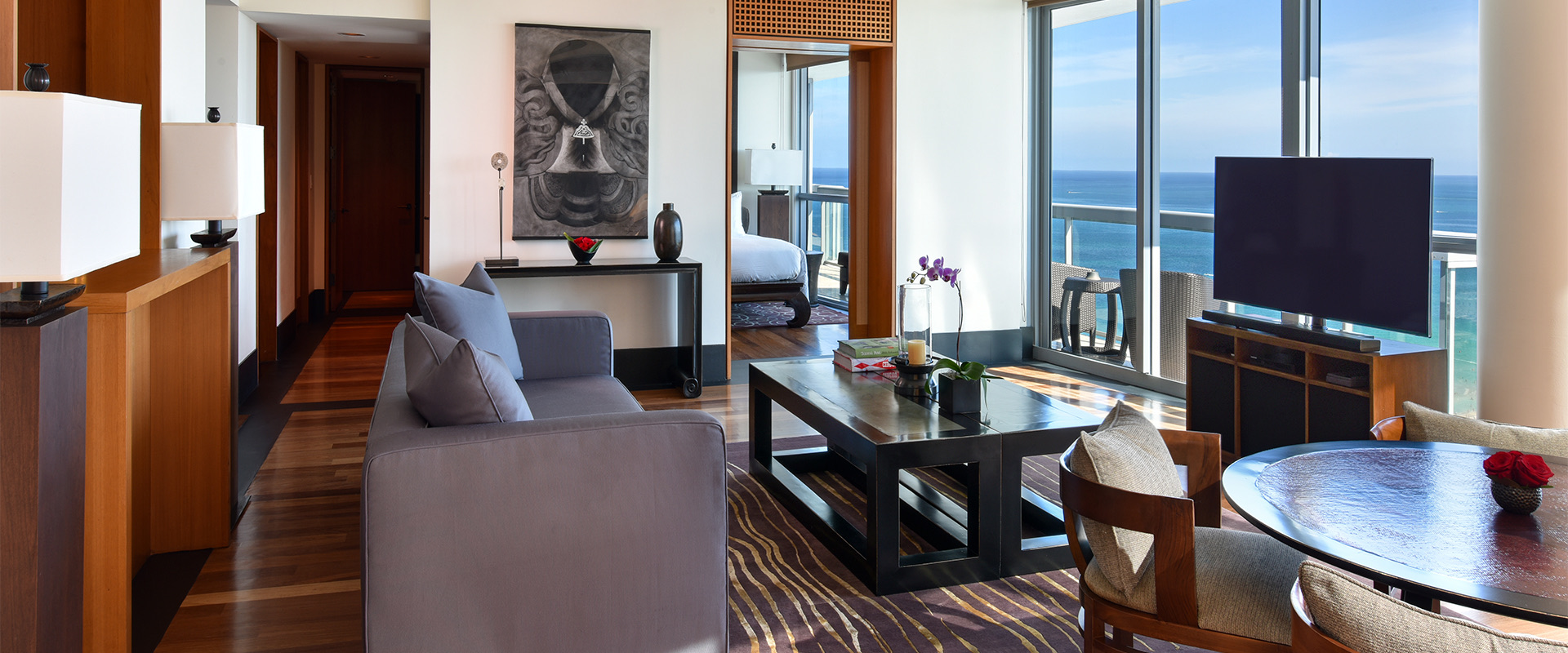 a large room with a sitting area and table for dining overlooking the ocean during the day