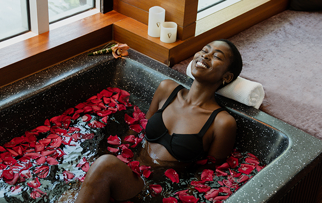 girl in a spa tub with red rose petals surrounding her in the water