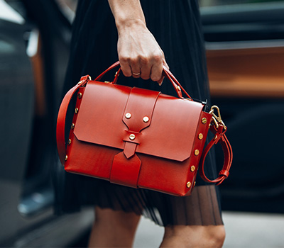 close up of a woman wearing a black dress and holding a bright red purse