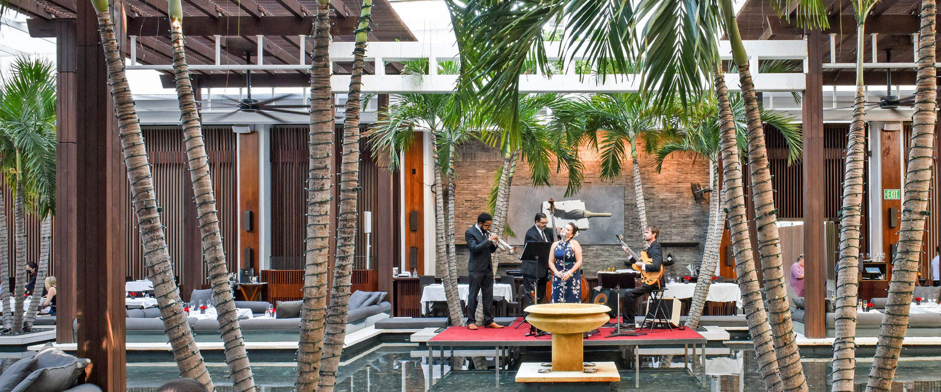 a stage with a band performing on it outside with tall palm trees