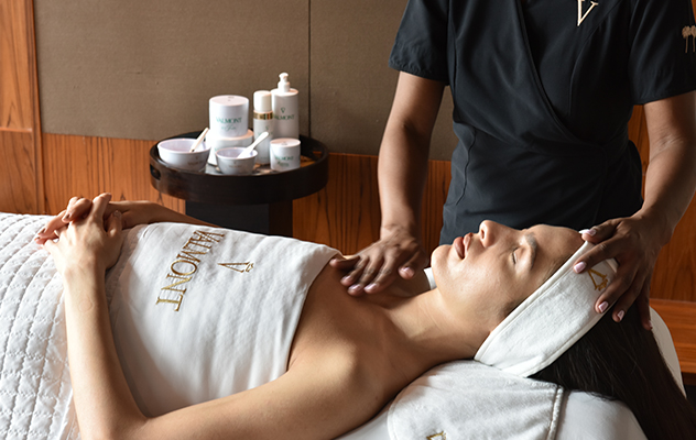 a woman laying with her hands crossed while getting a facial
