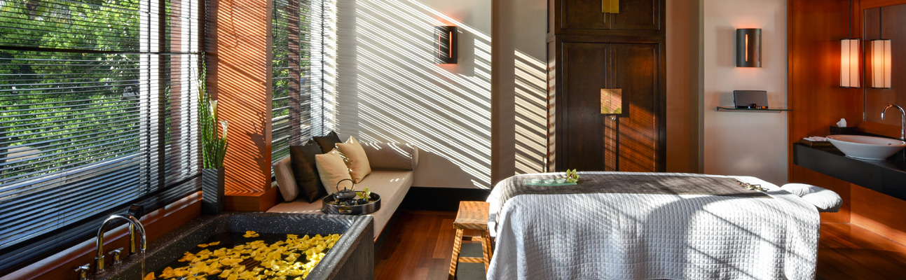 a room with a bathtub next to the windows filled with yellow flower petals and the sun shining in from outside
