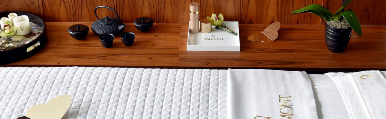 candles and a black tea kettle on a wooden table next to a massage bed