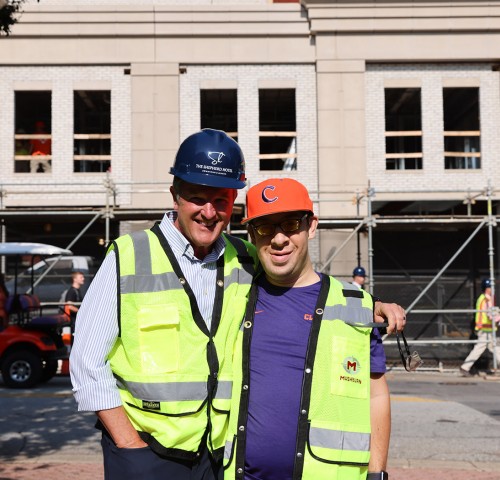 2 men smiling with construction vests on