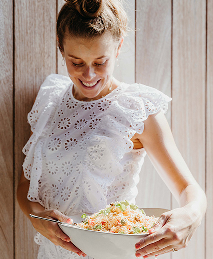 woman smiling at salad in bowl