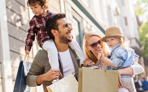 couple holding their two children in arms with shopping bags