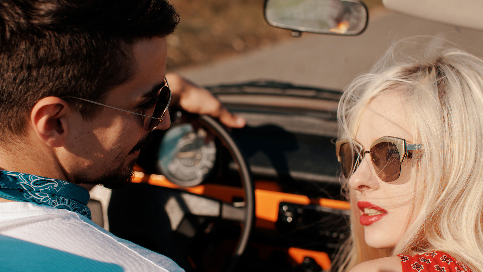 couple sitting in a car wearing sunglasses