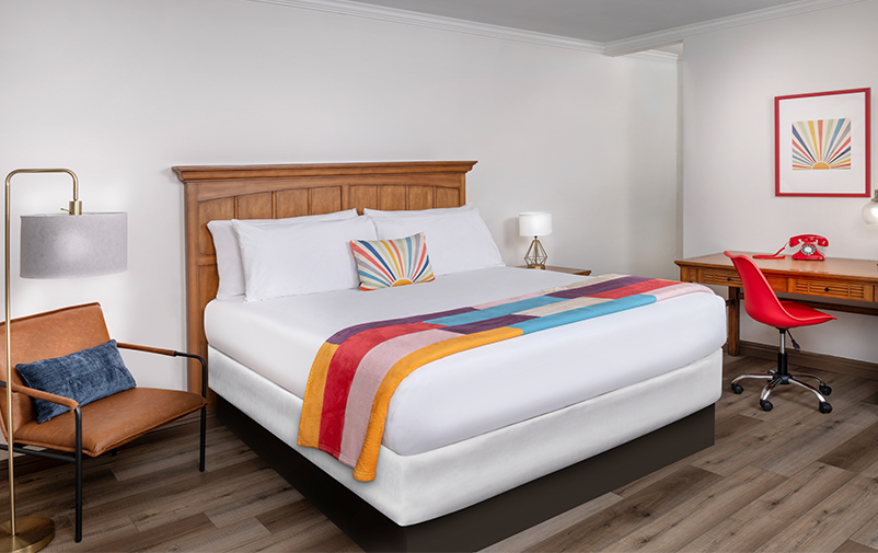 bedroom with hardwood floors, white bedding sheet and colorful throw blanket and pillow