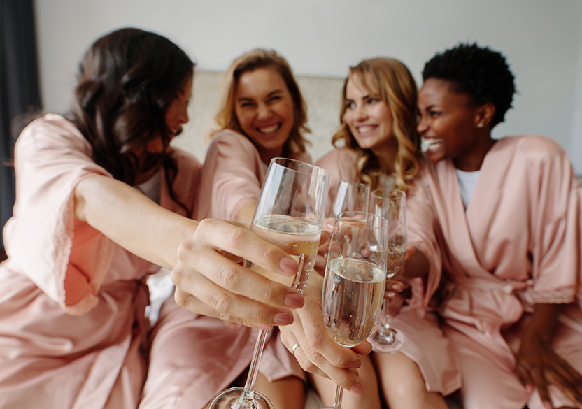 group of four women toasting with a glass of champagne