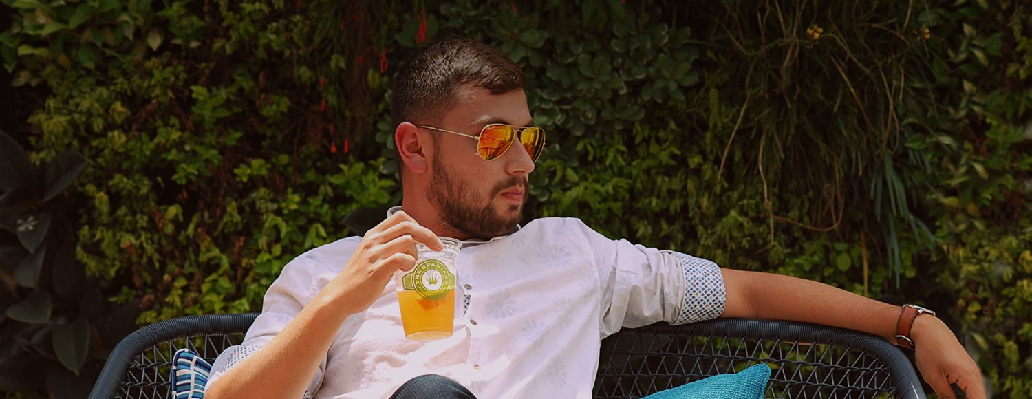 Man holding drink at outside chair