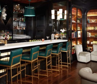 corner view of a empty bar with green furniture and accents
