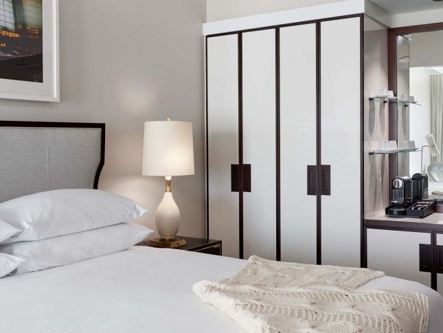 hotel bedroom view with features as a traditional closet, square mirror and a nightstand by the side of the bed