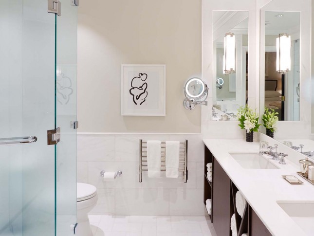 spacious and modish washroom of property with two sinks in white accents