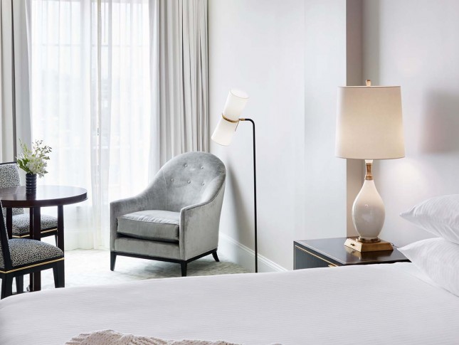 closeup view of a hotel room furniture as gray armchair, chairs and nightstand 