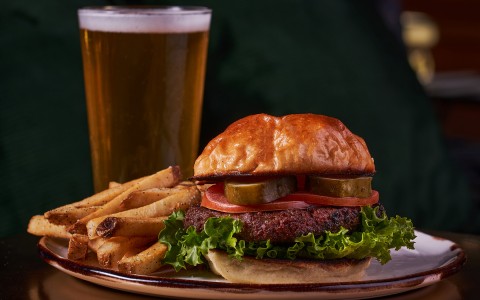 close up view of a burger served with fries and beer