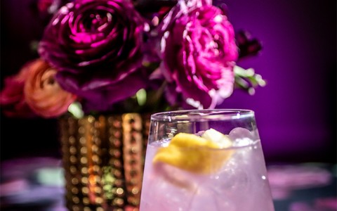 close up view of a cocktail with a buquet of flowers in the background