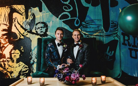 groom and groom posing for a pic in front of a wall with graffities