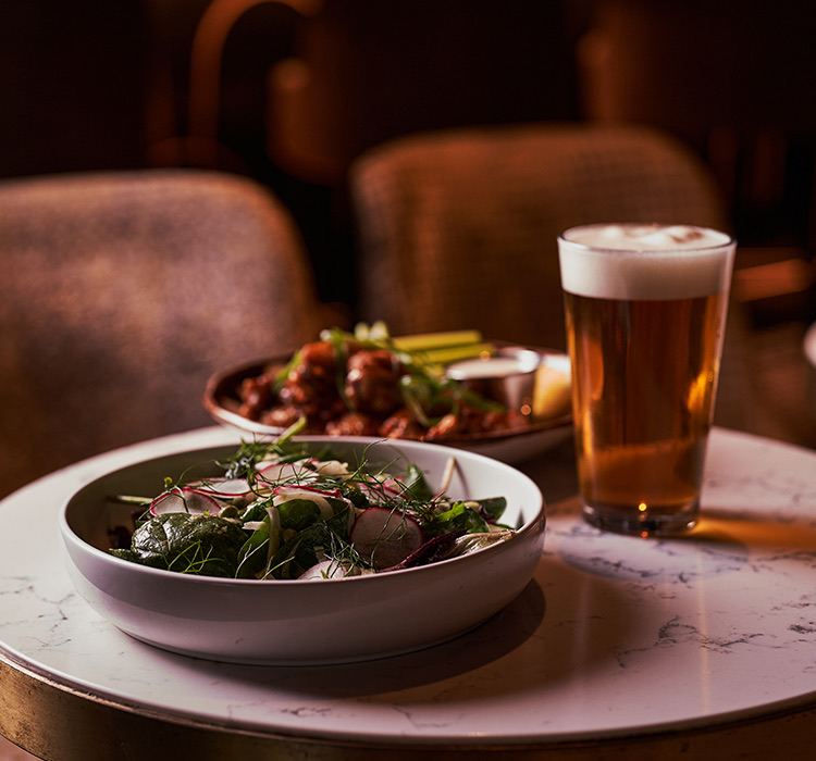 view of a dish of chicken wings, a salad and a glass of beer
