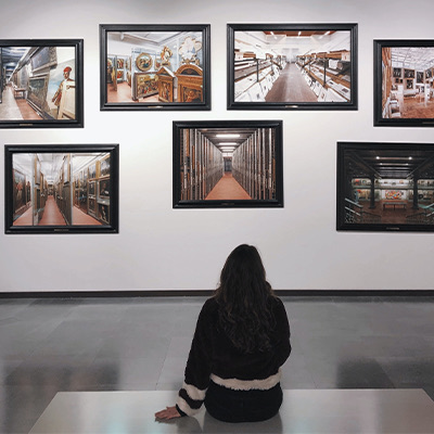 back view of a woman sitting on the floor in front of a paint gallery