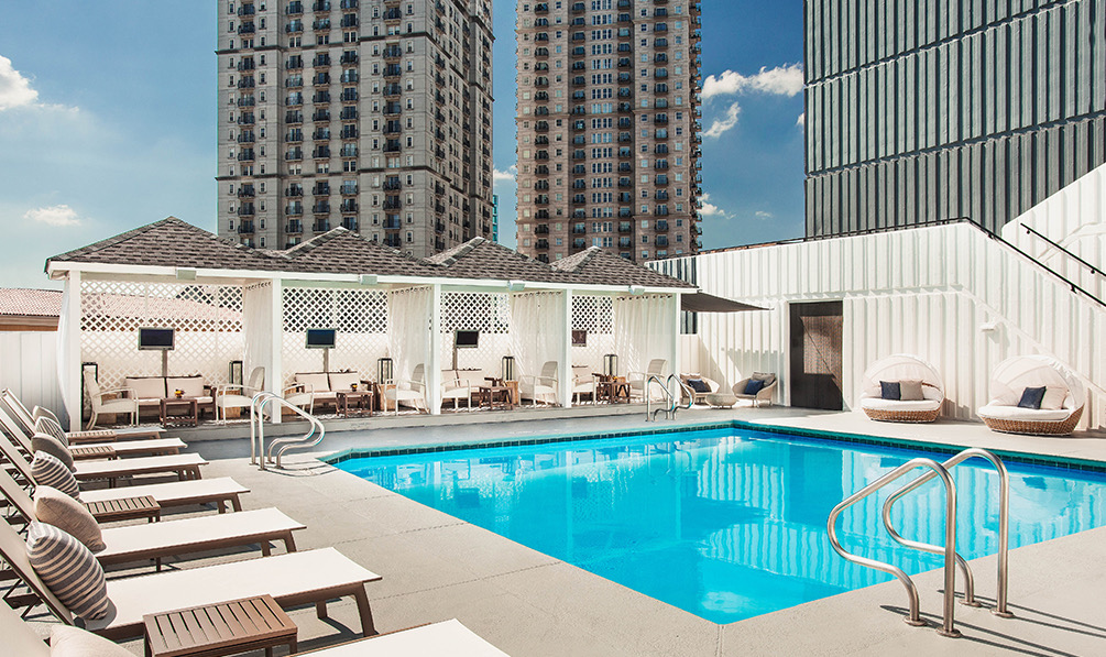 view of the rooftop pool surounded by sundeck lounge chairs