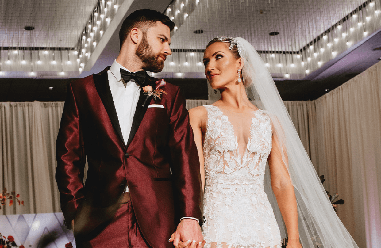 Groom and bride holding hands and looking at each other