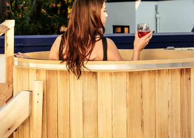 woman sitting in a cedar hot tub drinking wine