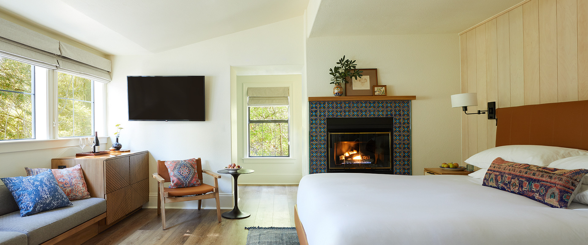 bedroom with one side of wooden panel walls, fireplace, and tv
