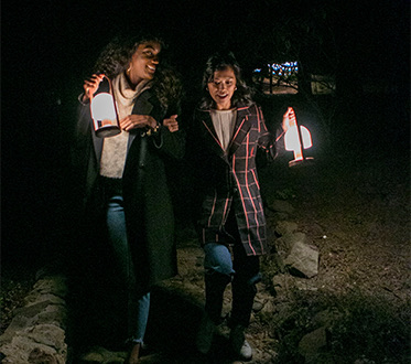 two people walking in the dark with lanterns
