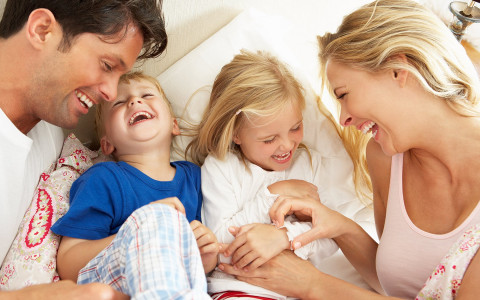 a family laughing together on a bed