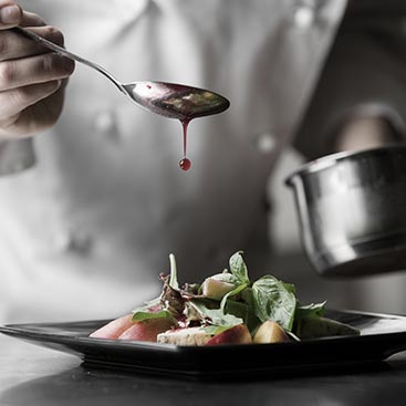 chef drizzling sauce on dish