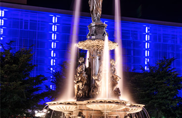 Water fountain & building with blue neon lights in the back