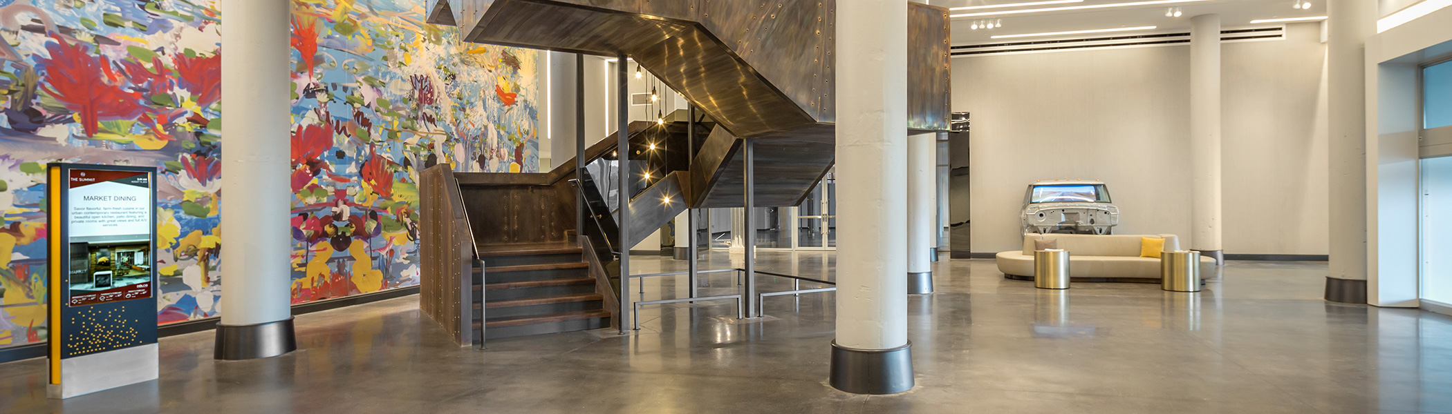 a lobby featuring a large staircase and artwork covering a full wall