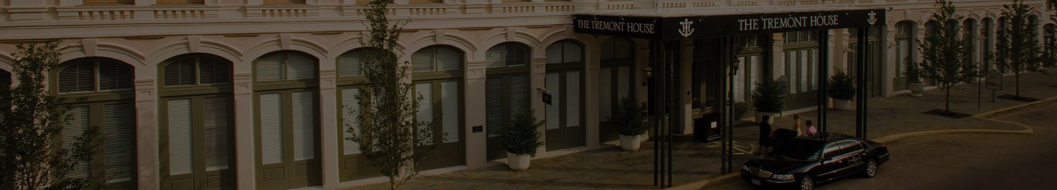 wide header image of hotel front with black canopy and car