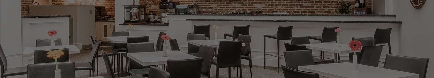 wide image of cafe seating area with white tables and black chairs