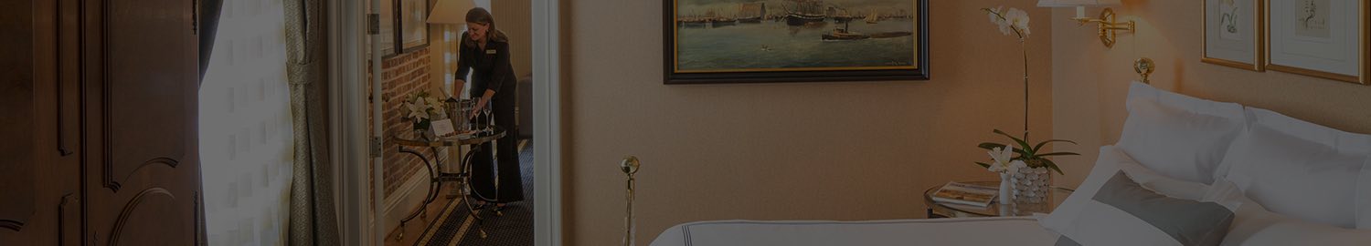 wide header image of white linen bed in brightly lit peach room