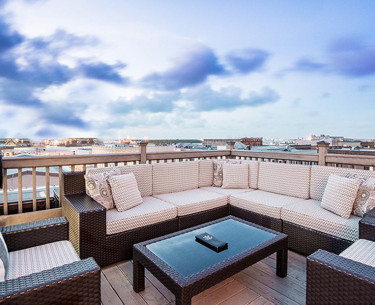 rooftop bar seating with brown wicker furniture against a blue cloudy sky